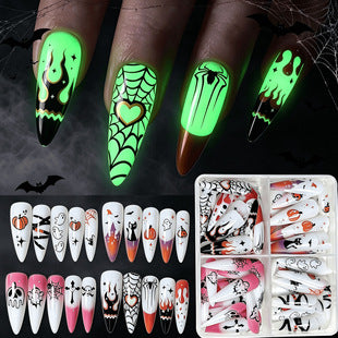 Close-up of spooky gothic Halloween fake nails with glow effect and festive ghost pumpkin designs