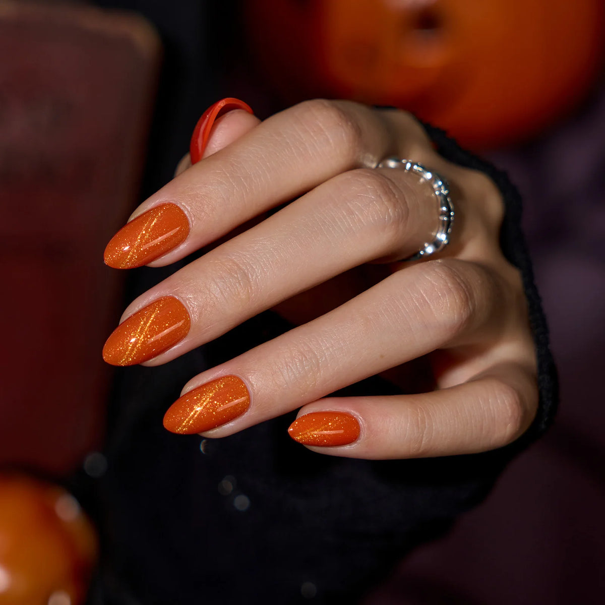 Orange cat eye press-on nails in an almond shape with handmade bling accents